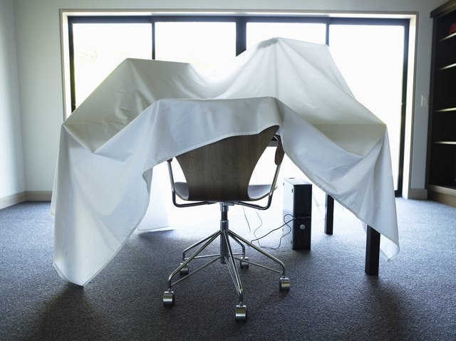 Desk, chair and computer covered with sheet