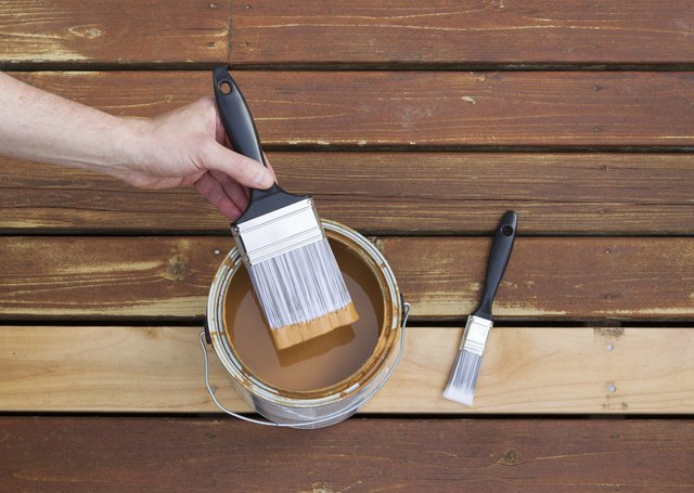 Dipping paint brush into a can of wood stain