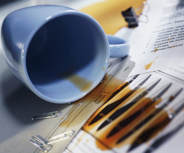 Overturned coffee cup; coffee spilled over papers and file folder