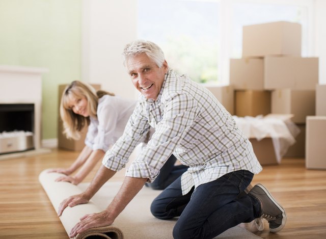 Couple unrolling carpet in new house