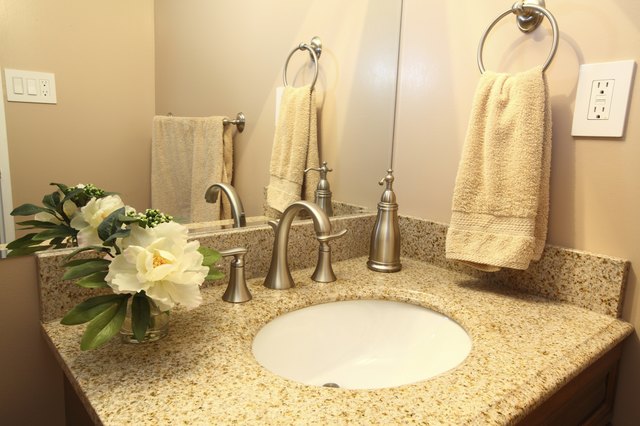 Modern bathroom vanity with beige granite top and faucets