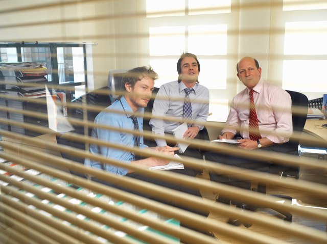 Three businessmen in meeting, view through glass panel