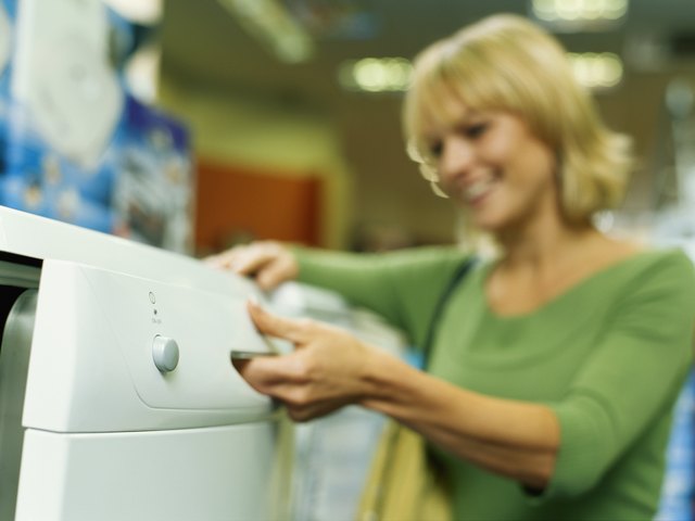 Woman in electrical shop opening washing machine