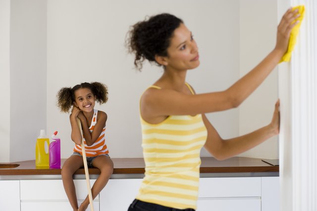Woman cleaning with girl looking on