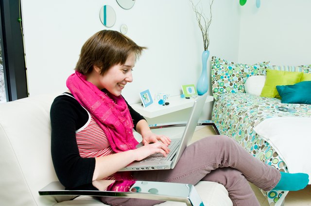 Woman using laptop computer in bedroom