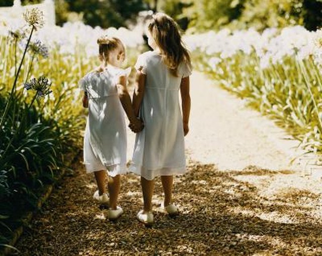 Rear View of Two Bridesmaids Walking Down a Gravel Path Between Flowerbeds