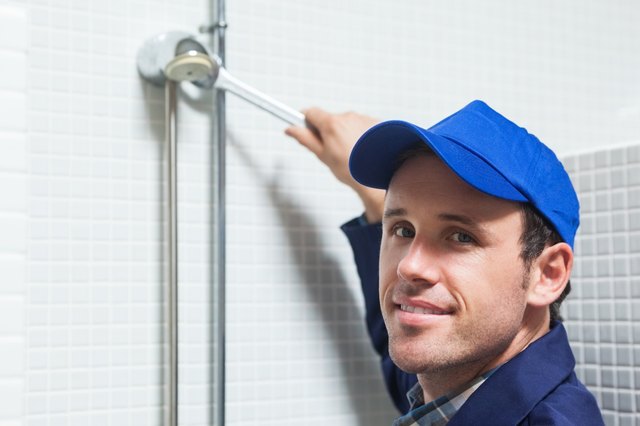 Cheerful plumber repairing shower head