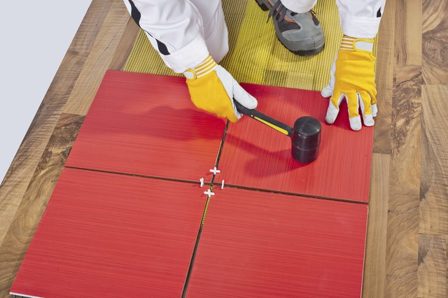 Worker Applies with Rubber Hummer Tile on a wooden Floor
