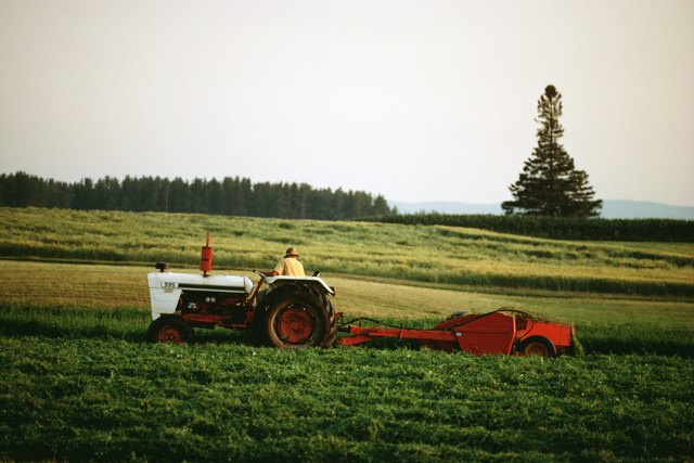 Farmer riding tractor through field, Canada