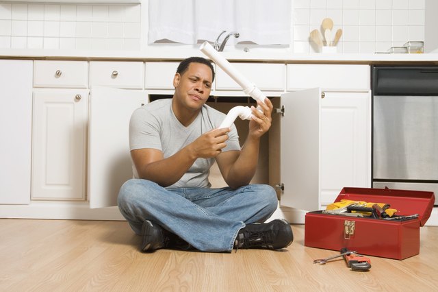 Man sitting on floor with pipe and toolbox