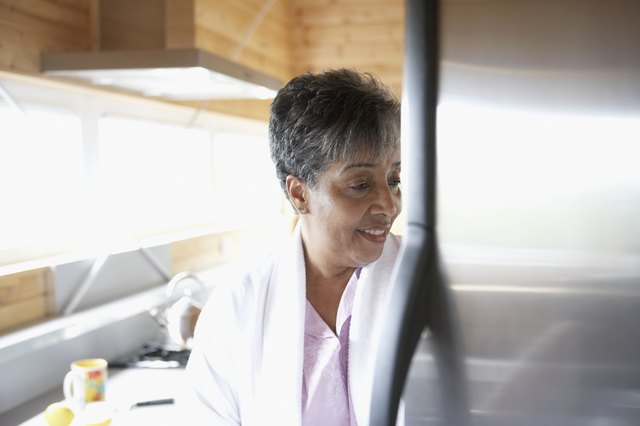 Senior African woman looking in refrigerator