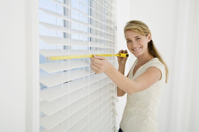 Woman measuring window blinds