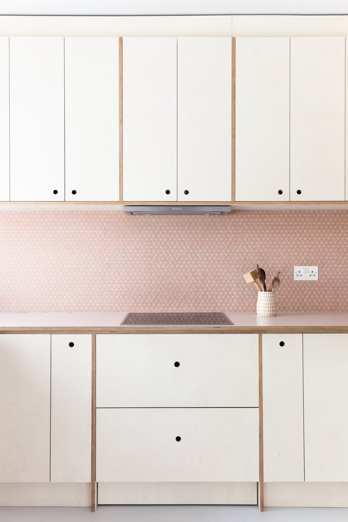 pink kitchen with pink tile backsplash and white cabinets