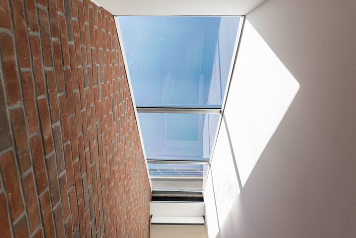 Looking-up shot of skylight with brick wall on left side and white wall on right side