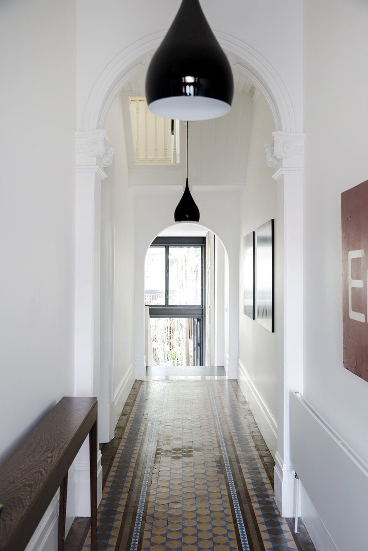Hallway with tiled floor, white walls and black pendant lights.