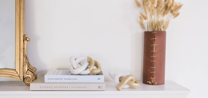 two diy clay knot sculptures on mantel with mirror, books and dried flowers