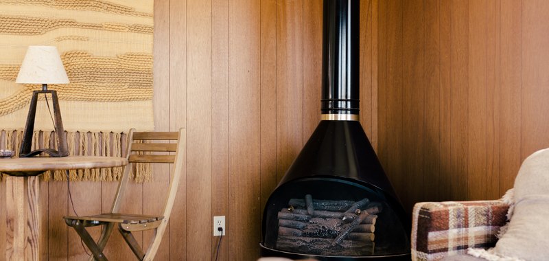 rustic decor with a wood-burning stove in the corner of a room with retro wood paneling